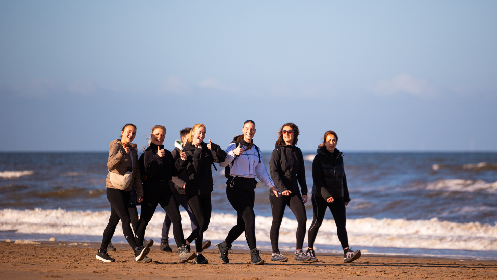 wandelaars op het noordzeestrand tijdens de 30 van zandvoort met duinen van nationaal park zuid kennemerland op de achtergrond